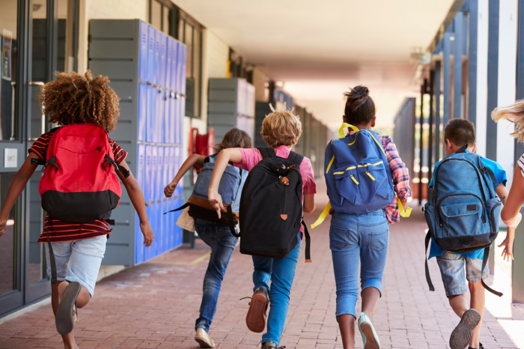 Enfants avec leurs cartables dans un couloir d’école.