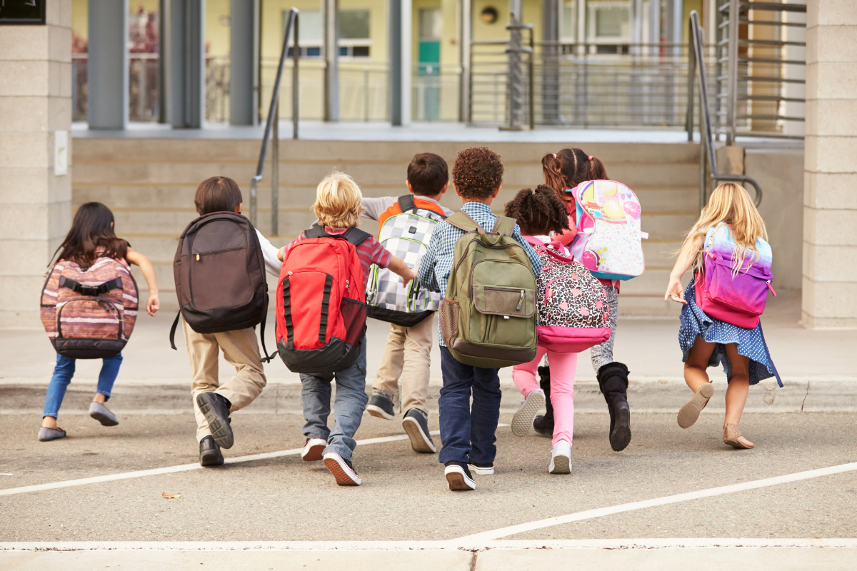 Enfants de dos se dirigeant vers une école.